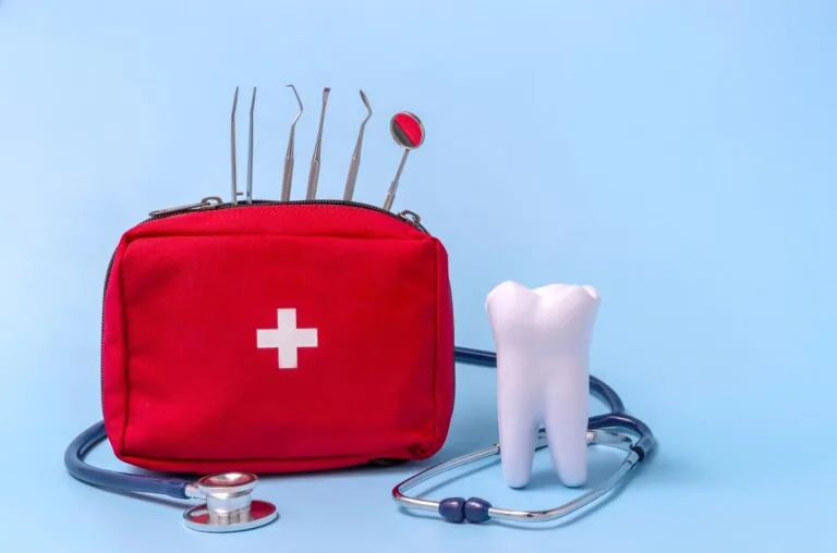 a model of a tooth, a stethoscope, a dentist's tool, a first aid kit. concept first aid for toothache.